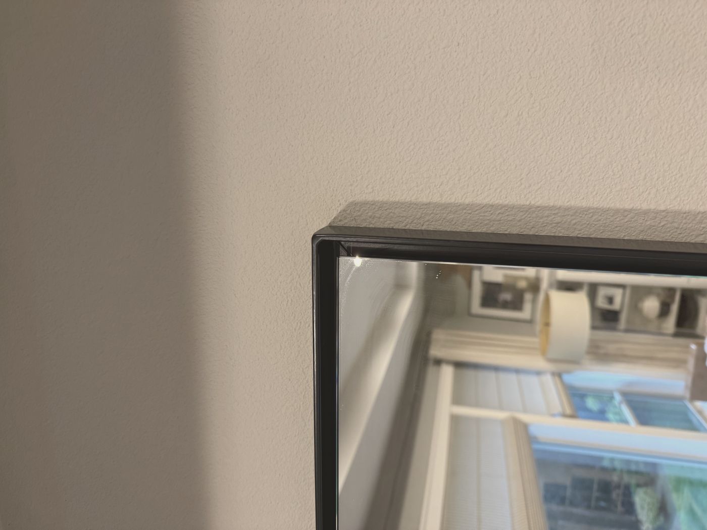 Close detail of the mitered top corner, showing the eighth-inch steel edge and the frame standing clear of the wall.